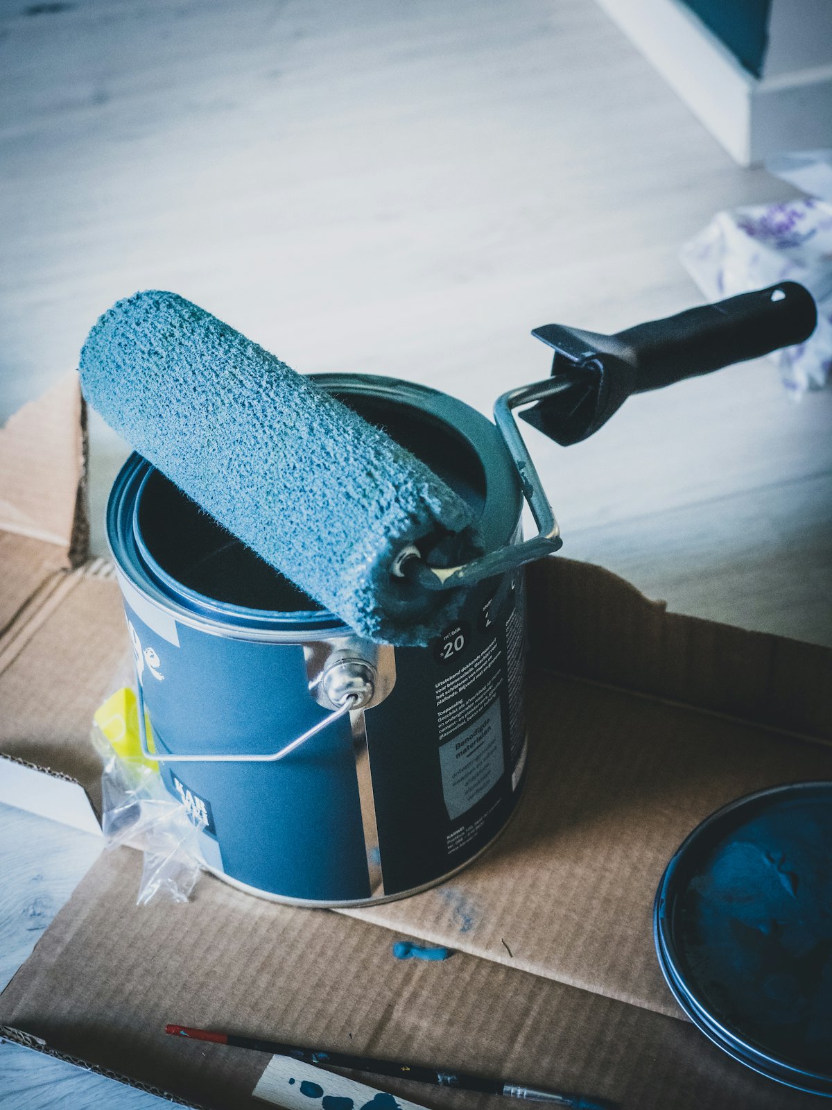 Verfroller op een open pot blauwe verf